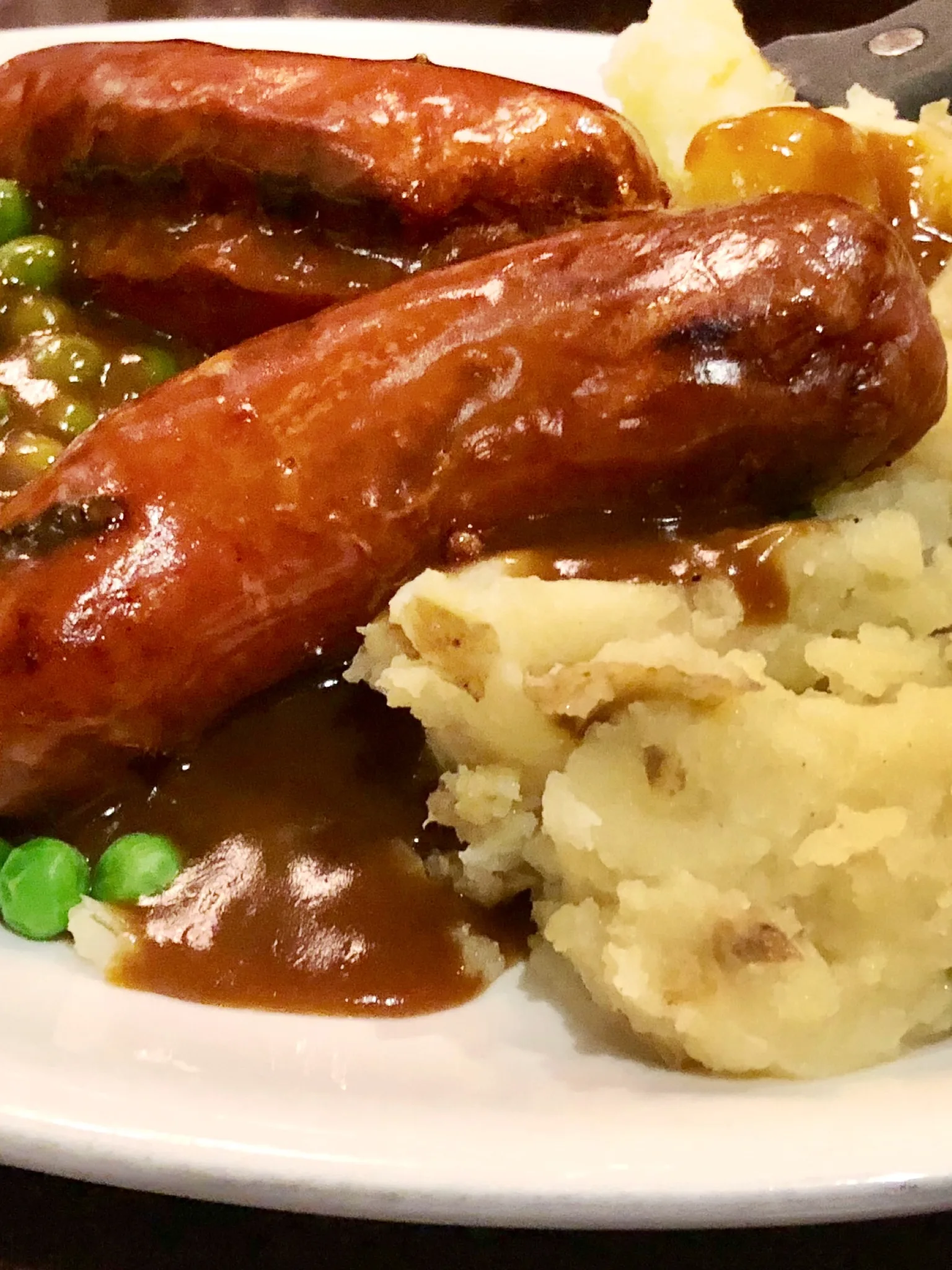 bangers and mash: A plate of sausage, mash, peas and gravy