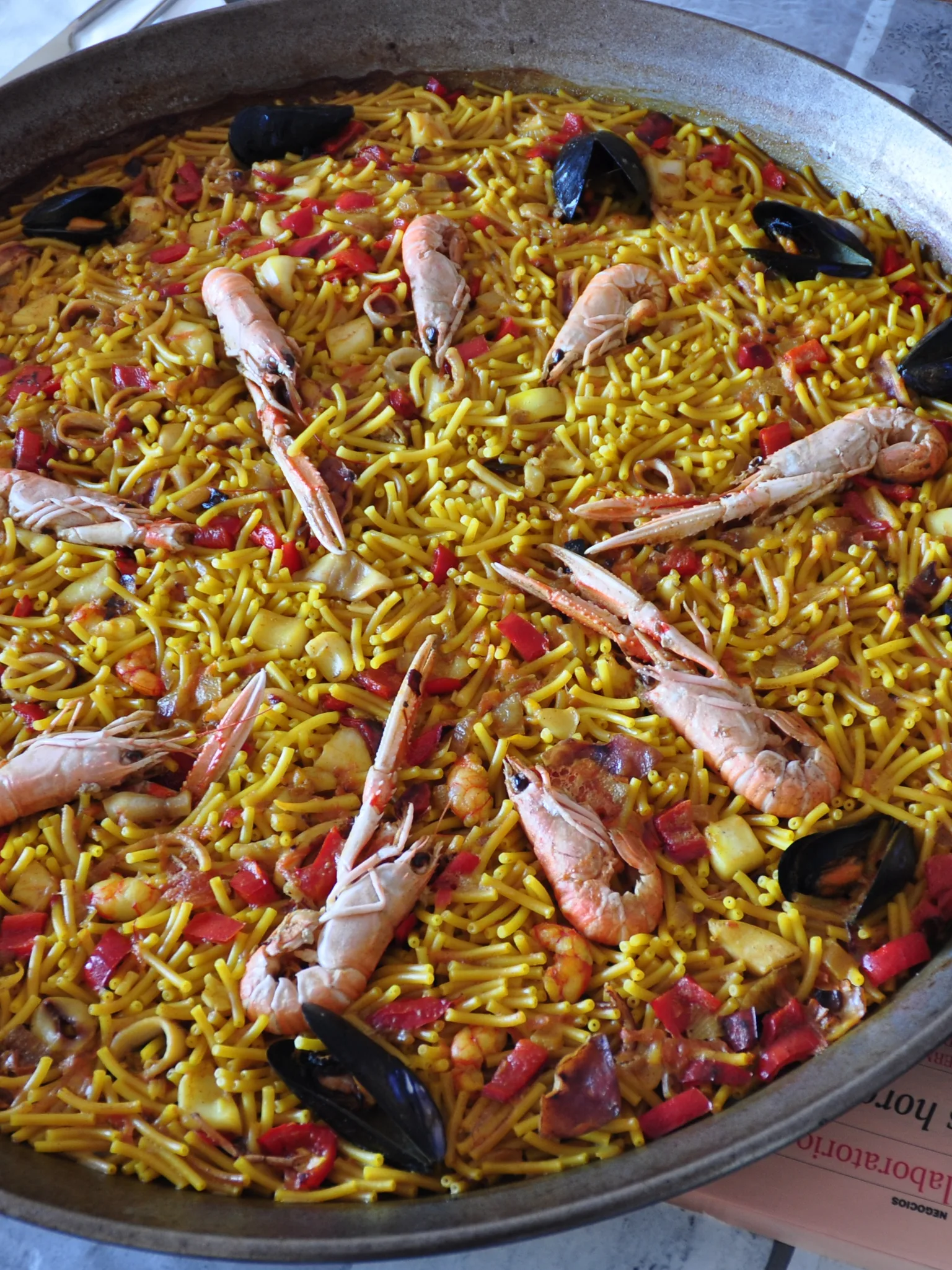 fideuà: Una paella de fideuá, con alioli como complemento