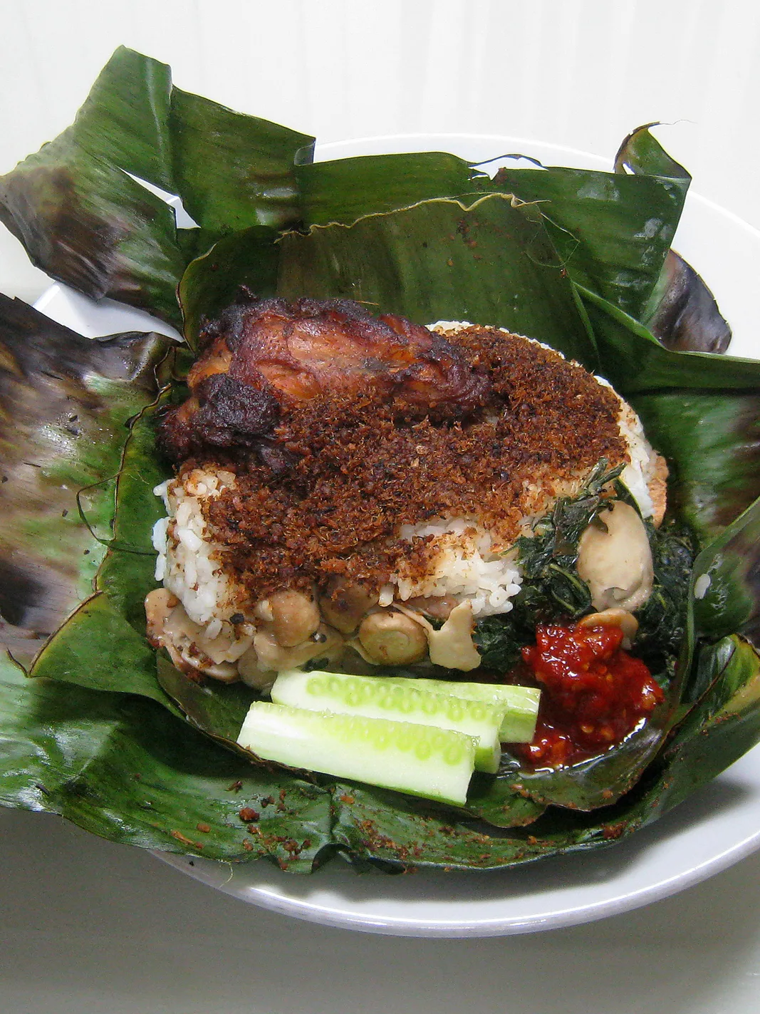 Nasi bakar: Nasi bakar, a seasoned and spiced rice cooked (grilled) inside banana leaf, served with ayam goreng (fried chicken) with mushroom, vegetables, and spicy chilli sambal. Jakarta, Indonesia