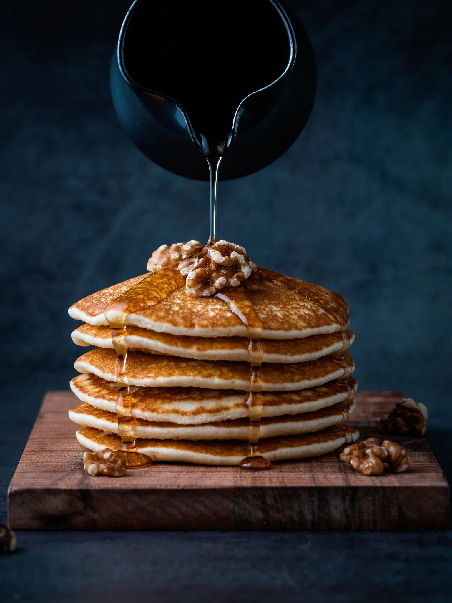 pancake: Honey poured on american pancakes. Walnuts are on top of the stack of pancakes